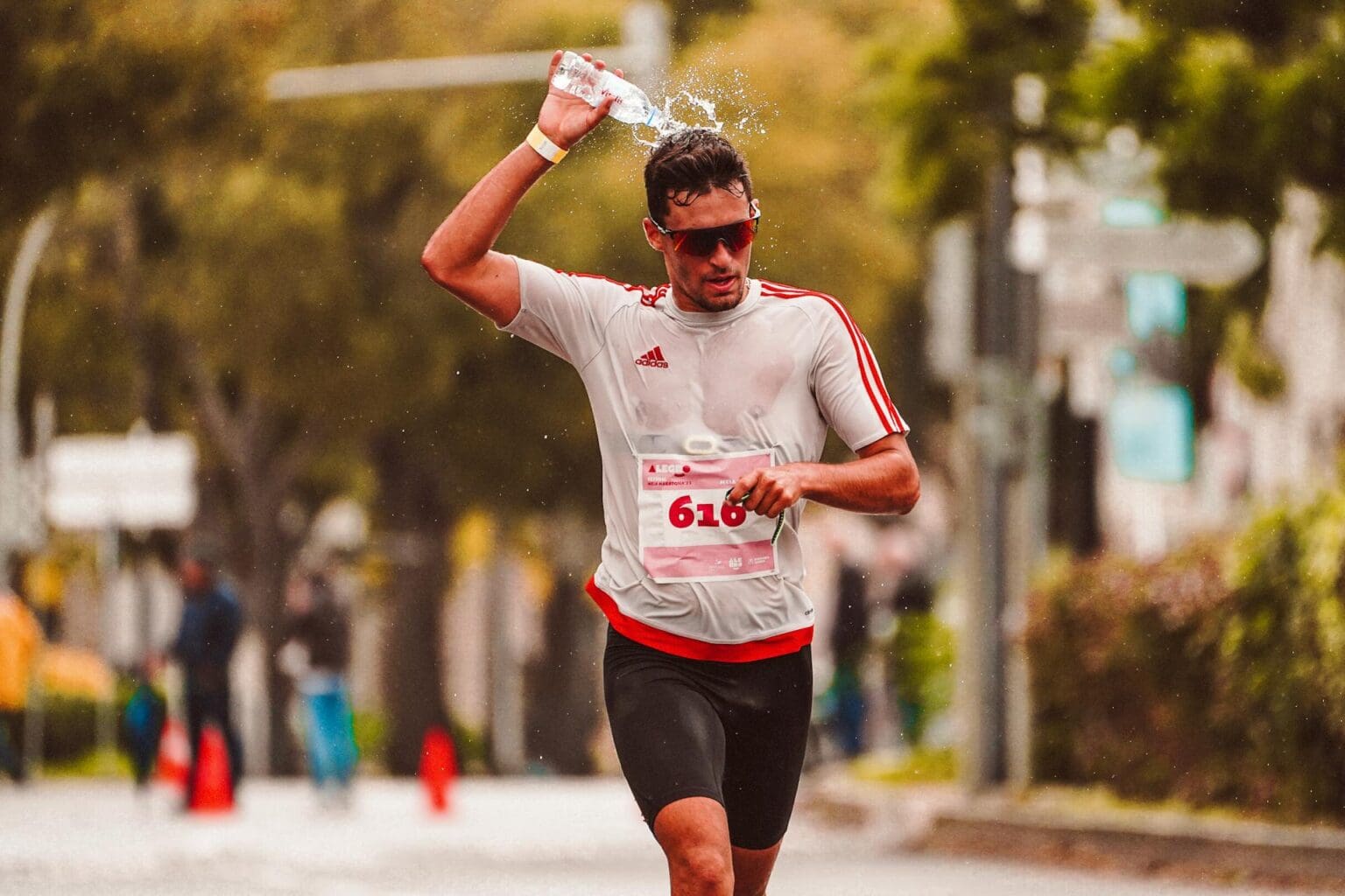 6 Best 10k Running Shoes (2026): Top Picks for Race Day man pooring water on himself after finishing a race