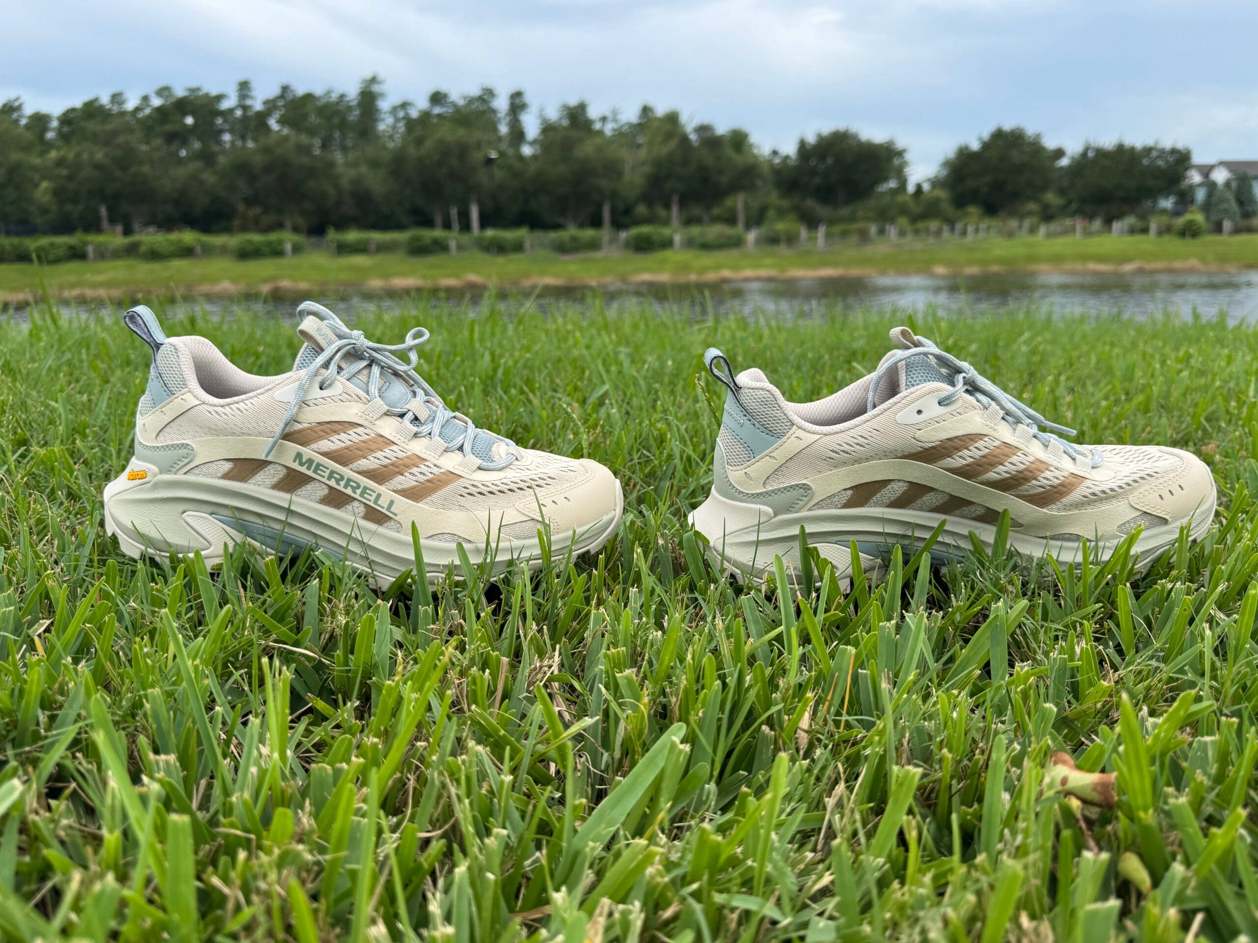 Merrell Moab Speed 2 in grass side by side with pond in back