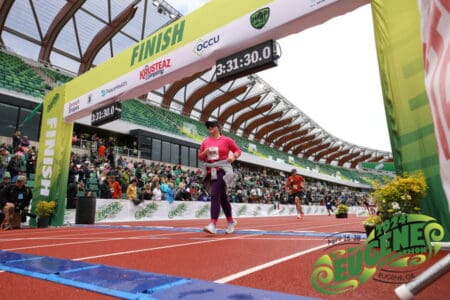 girl running the eugene marathon crossing the finish line