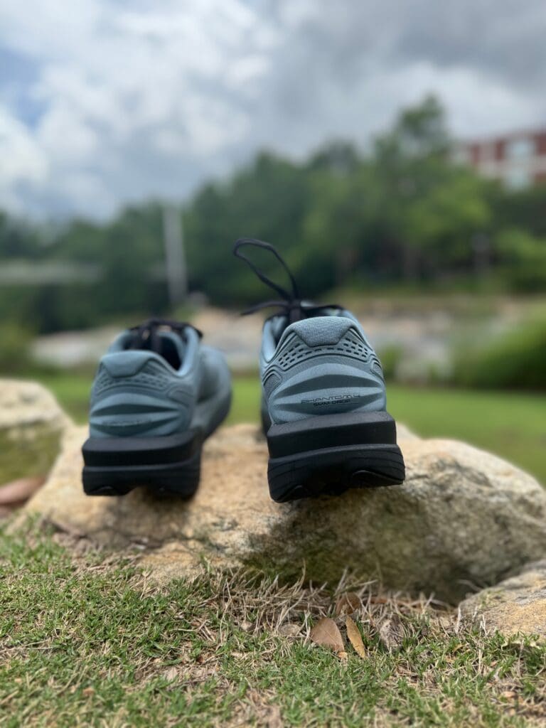 Topo Athletic Phantom 4 heel and back of shoe on rocks with river and park in background
