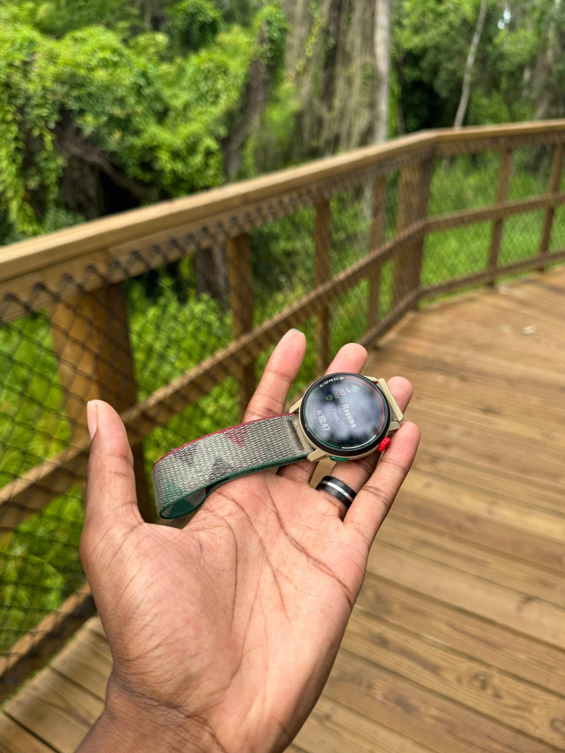 coros pace 3 in hand with trail bridge in background