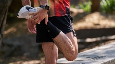 man stretching out shins before run