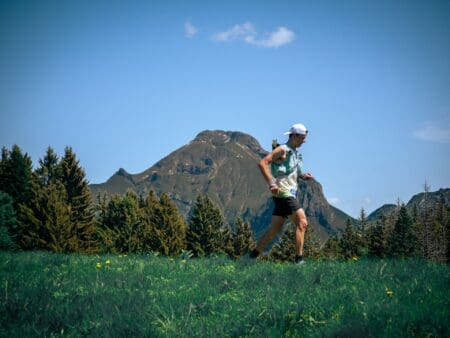 man running on trail in mountains with hydration running vest