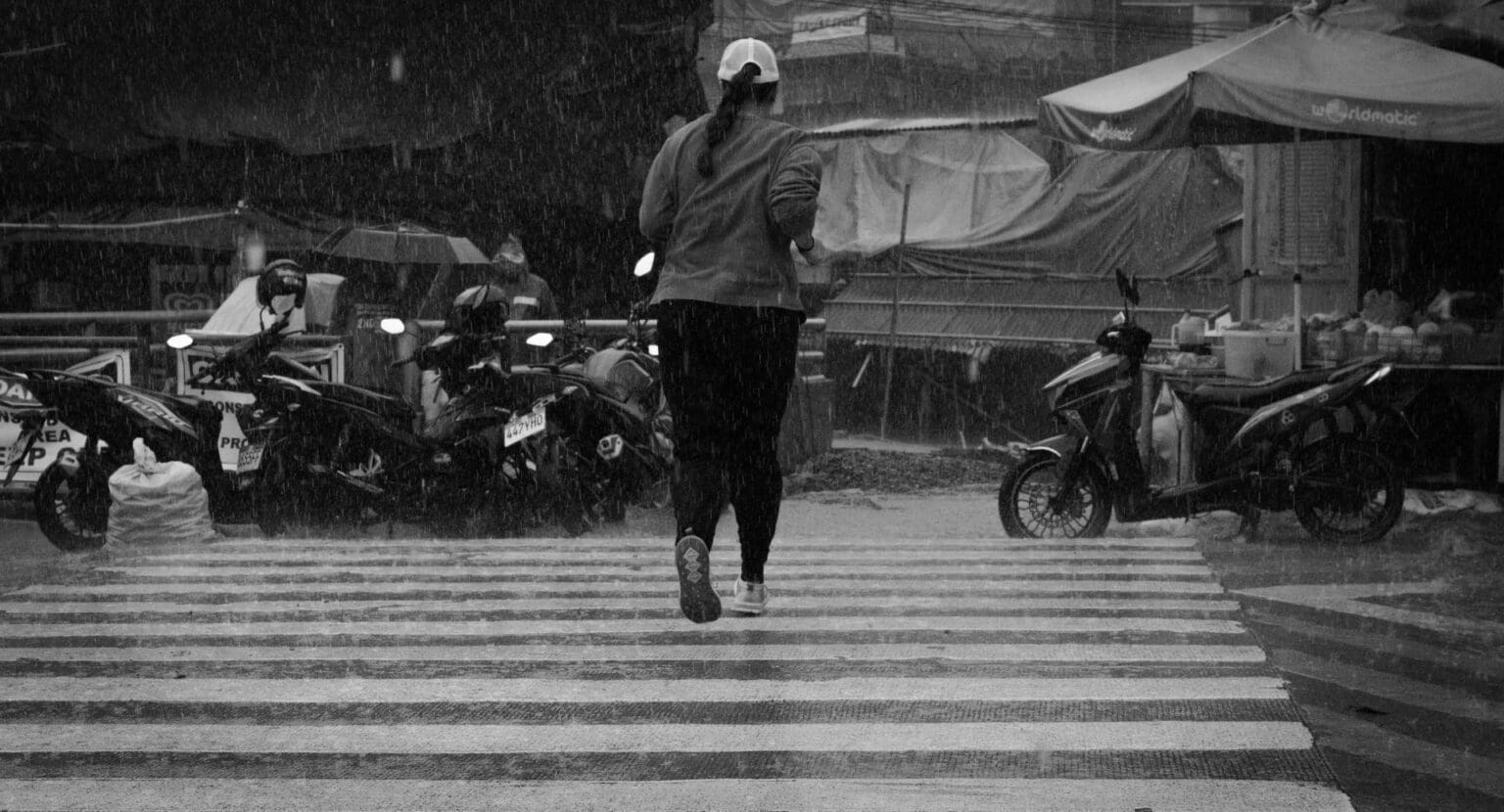 6 Best Waterproof & GTX Shoes for Running in the Rain (2026) girl running across cross walk in the rain