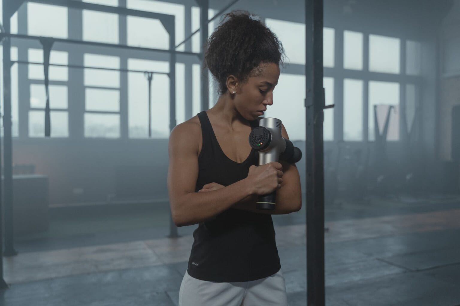 girl using massage gun in gym