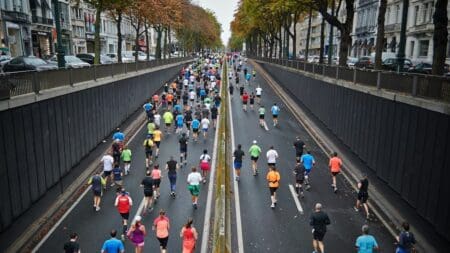 6 Best Running Shoes for Achilles Tendonitis Aerial view of a large pack of marathon runners competing in a city road race through an asphalt street underpass