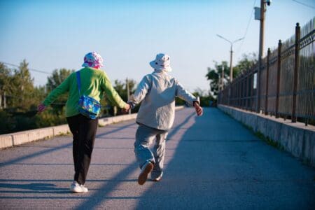 The Benefits of Walking as You Age: Health, Balance, & Longevity happy older couple walking together through a park