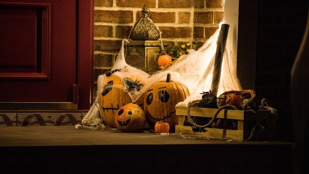 Halloween Running Scavenger Hunt: 31 Spooky Things to Spot on Your October Walks and Runs Front porch decorated for Halloween with painted pumpkins, spiderwebs, and a warm glowing lantern beside a brick wall