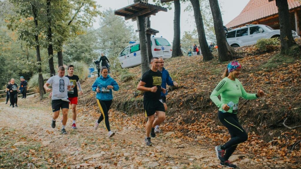 36 Halloween-Themed 5Ks, Races, Runs & Walks in West Central Florida: October 2026 Calendar Group of trail runners running downhill through golden autumn fallen leaves in a forest